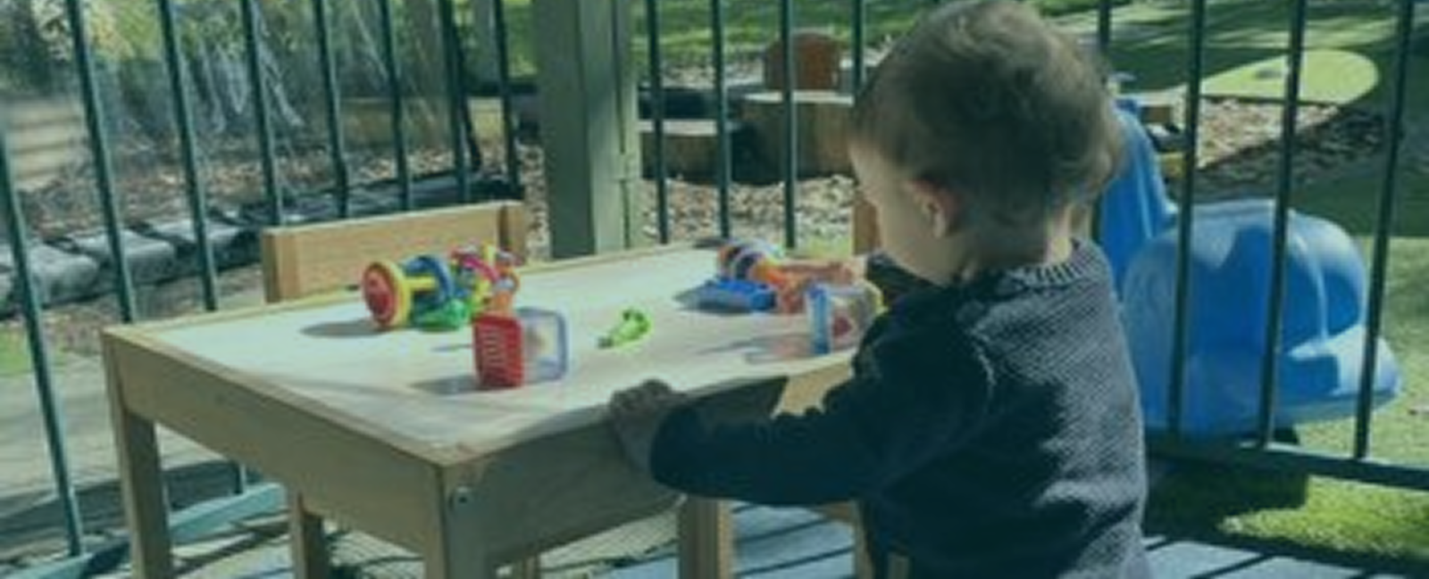A toddler engaged in play with colorful toys on a wooden table, showcasing a joyful learning environment.